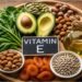 bntamnh e vitamin E rich foods including almonds sunflower seeds spinach and avocado on wooden table